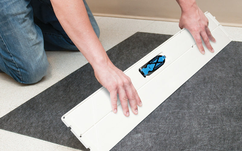 Insitu image of grey, non-slip SmartGrip matting with optional cutting board and safety knife being installed into a restroom floor.